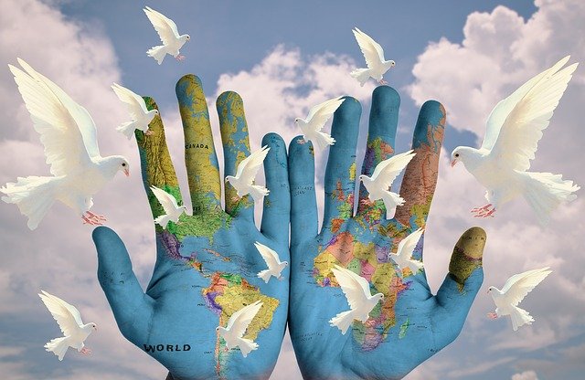 2 Hände mit politischer Weltkarte vor Himmel mit Tauben; Bild von S. Hermann, F. Richter auf Pixabay